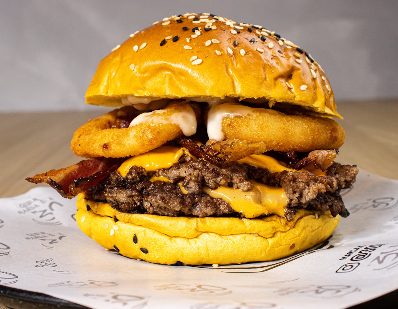 Mouthwatering cheeseburger with beef patty, bacon, and onion rings on sesame bun.