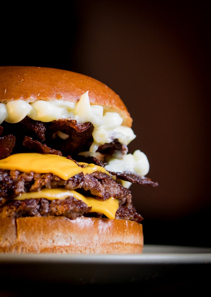 Mouthwatering close-up of a gourmet cheeseburger with two beef patties, bacon, cheese, and sauce.
